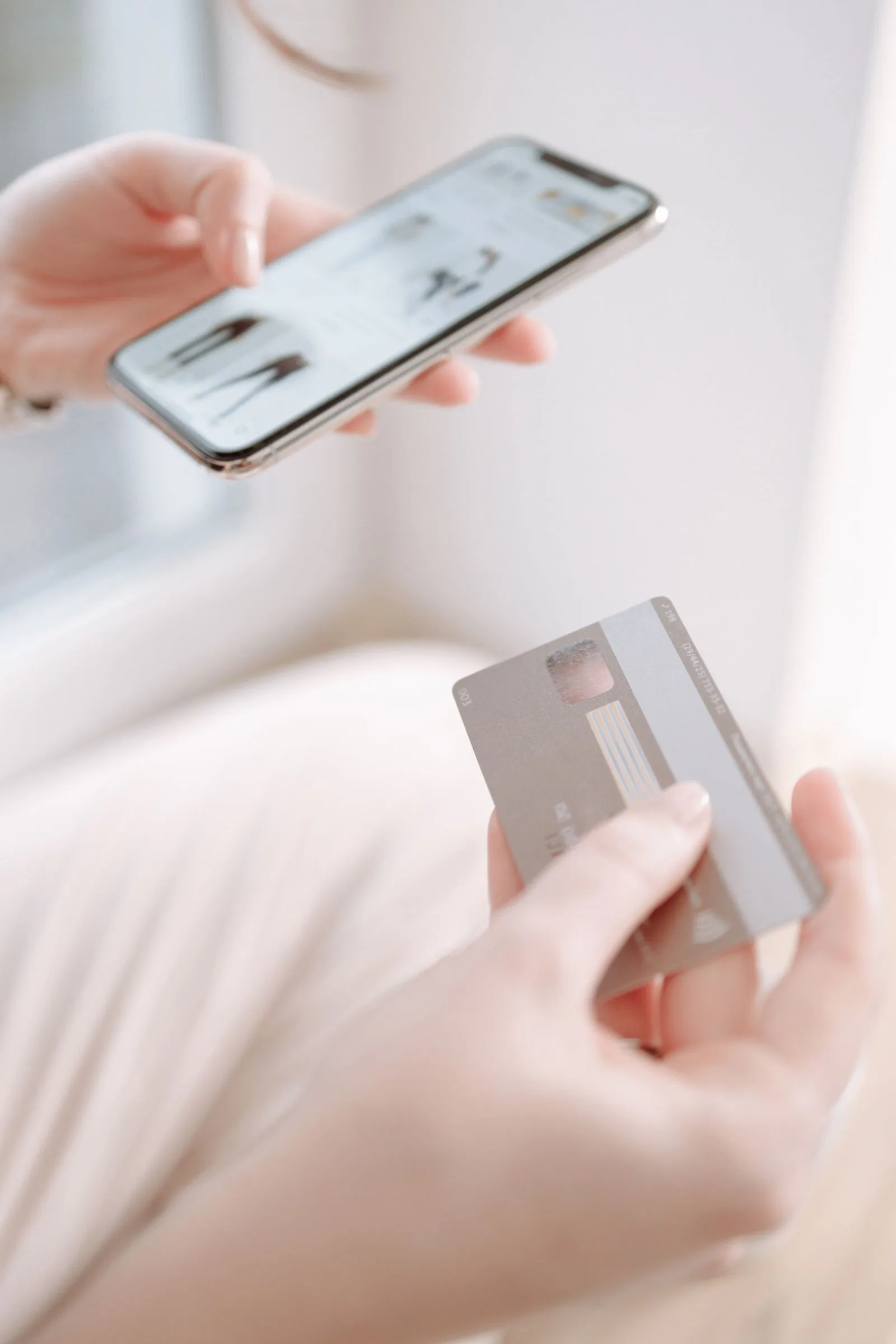 Cliente finalizando uma compra pelo celular com cartão em mãos